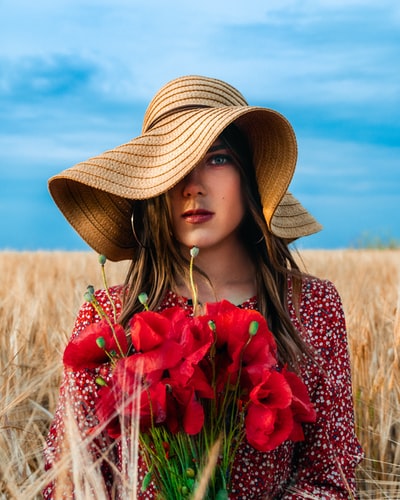 戴棕色草帽手持红花的女人